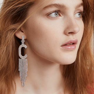 Close-up of a woman wearing a sparkling earring with a 'C' design.