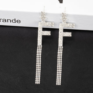 Silver cross-shaped earrings with beaded details on a black stand with 'Garde' branding.