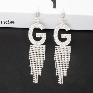 Silver earrings with 'GG' design on a black background