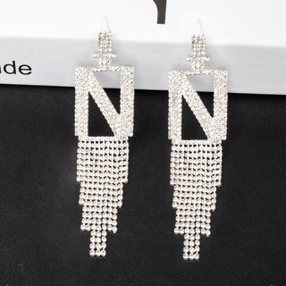 Pair of smoddo letter n silver tassel earrings on a black card with visible brand name.