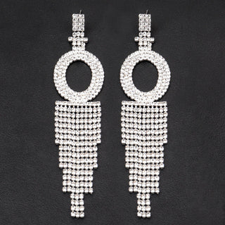 Pair of silver hoop earrings with tassel design on a black background