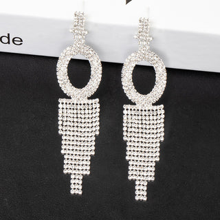 Silver earrings with circular top and tassel-like bottom on a black background