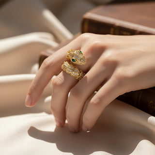 SMODDO Close-up of a hand wearing SMODDO adjustable snake ring in gold with green gemstones on a neutral background