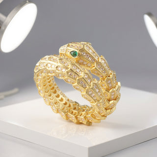 SMODDO adjustable snake ring in Gold snake-shaped ring with green gemstone on a white platform