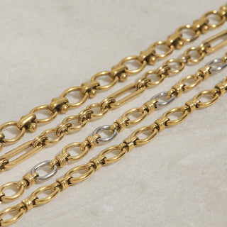 Gold chain with silver clasp on a light beige background