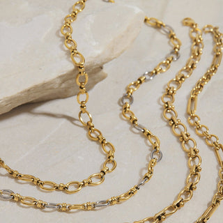 Two gold chains on a light stone surface