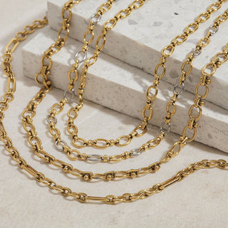 Gold chain necklaces on a light stone surface