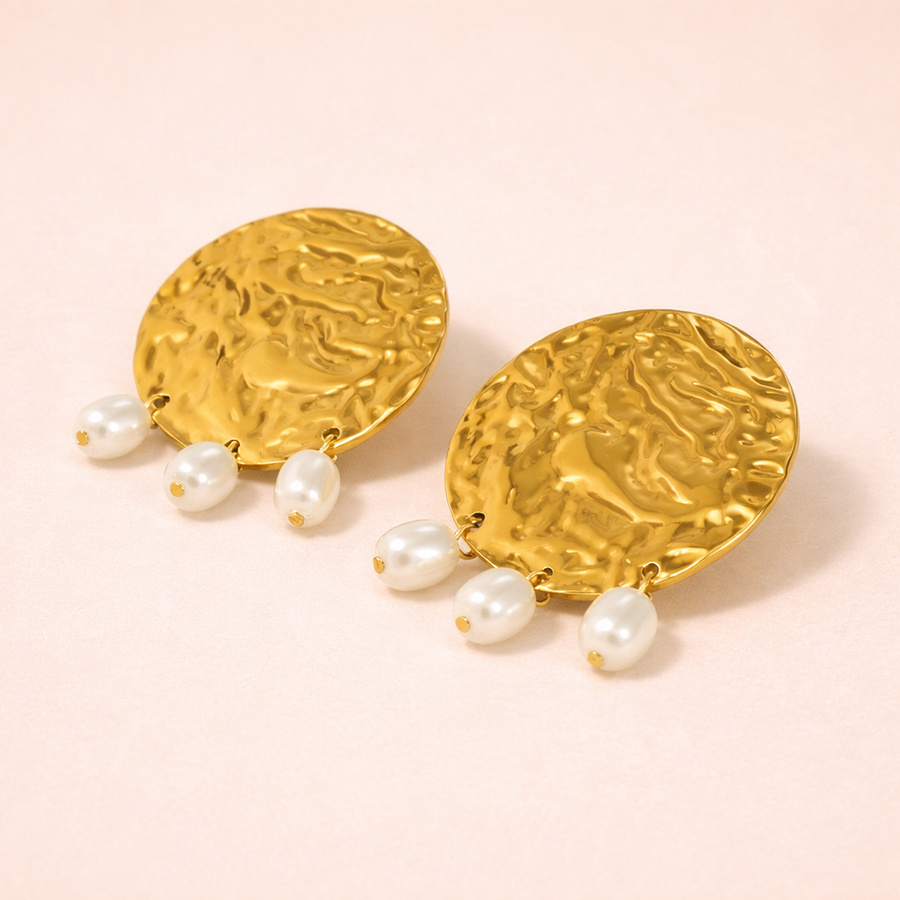 Gold earrings with pearl drops on a pink background