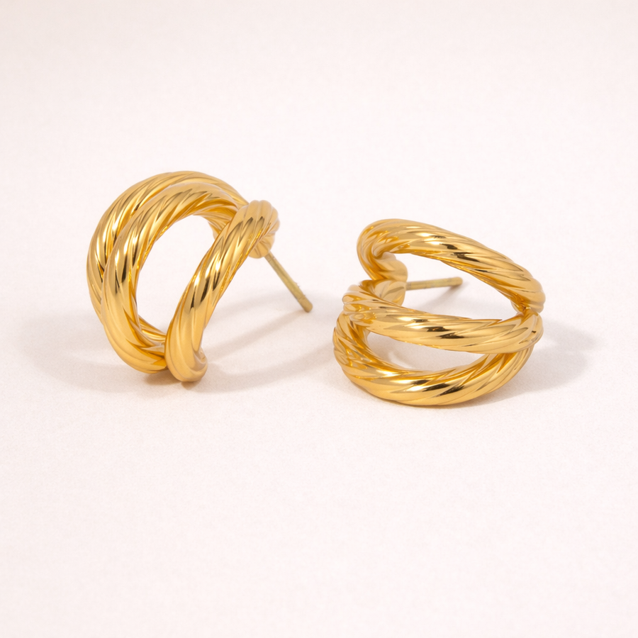 Pair of gold hoop earrings on a light pink background